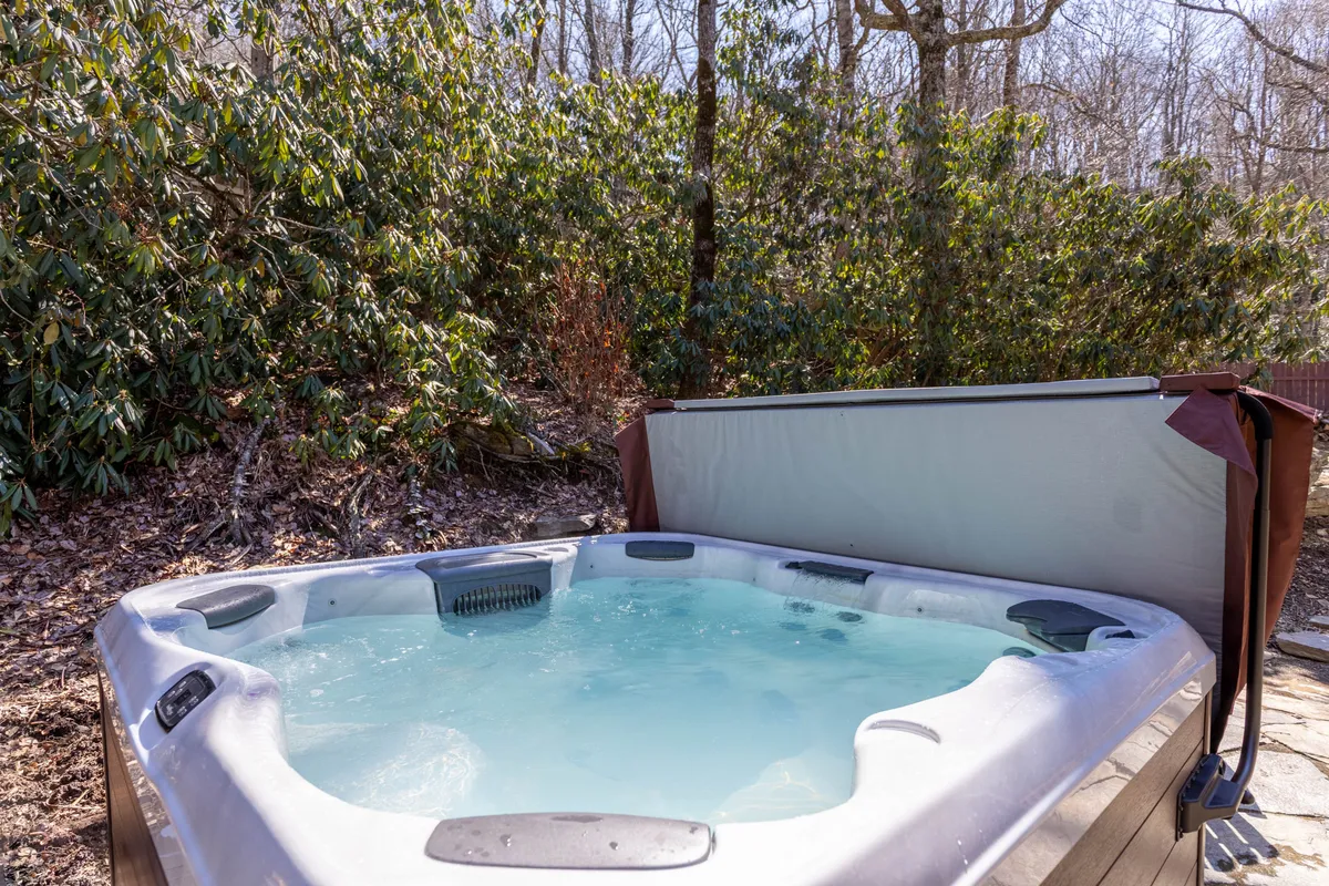 This exterior shot features a private hot tub nestled amidst lush greenery, inviting guests to relax and unwind while enjoying the tranquil natural surroundings. The setting is secluded and serene, emphasizing the connection to the outdoors and the luxurious amenities available for relaxation after a day of exploration.